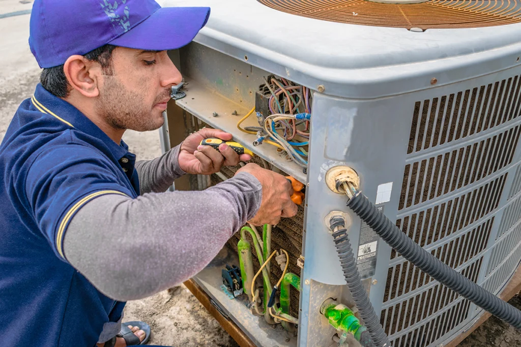 HVAC technician repairing the electrical components inside an outdoor AC condenser unit. Best for blogs about AC repair, condenser troubleshooting, HVAC service, and outdoor unit maintenance.