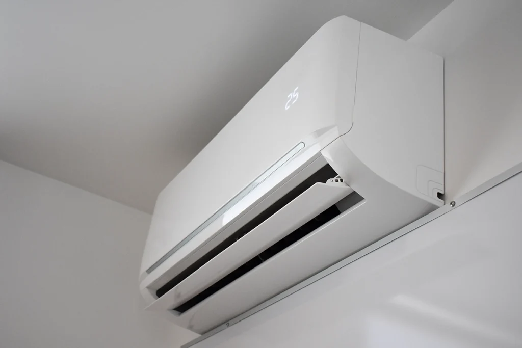 Wall-mounted ductless mini split indoor unit installed near the ceiling with digital temperature display. Best for blogs about mini split installation, ductless AC systems, mini split vs central air, ductless heating and cooling, best rooms for a mini split, and how mini splits work.