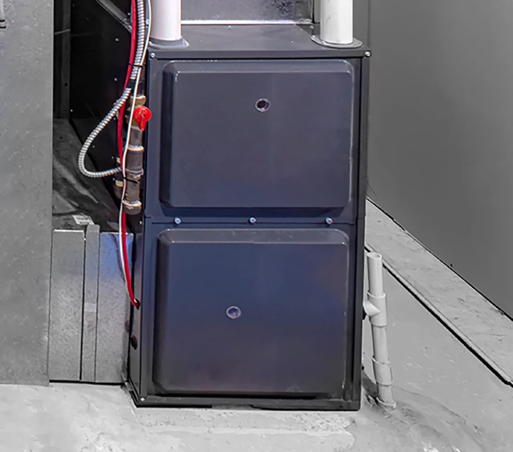 Gas furnace installed beside ductwork and condensate piping in a basement or utility area. Best for blogs about furnace installation, gas furnace basics, heating system overview blogs, what a home furnace does, and heating maintenance.